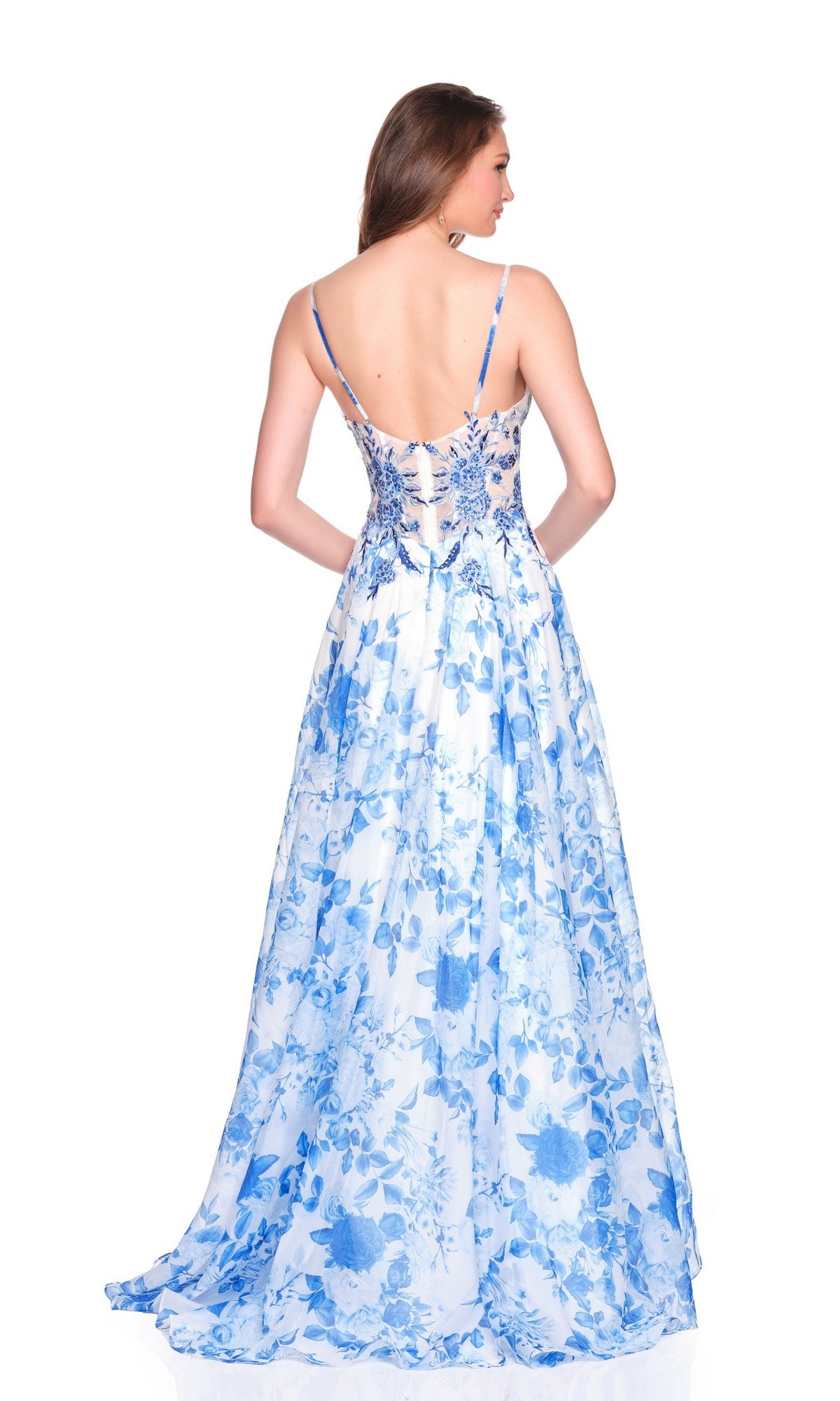 A woman stands with her back to the camera in a sleeveless, floor-length Dave and Johnny 12684 prom dress featuring blue floral patterns and a chiffon corset bodice, set against a white background.